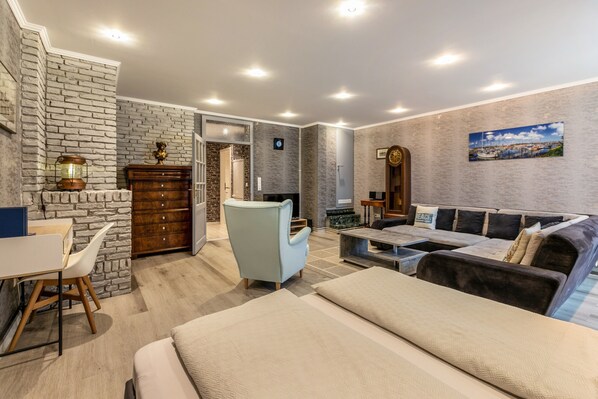 A modern hotel room with a stone accent wall, a sofa, a desk, and a bed.