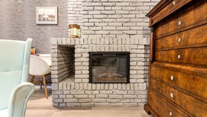 Une cheminée en pierre avec un meuble en bois à côté.