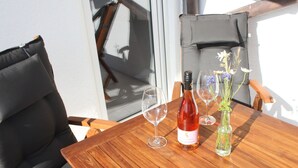 Ein Holztisch mit einer Flasche Rotwein, zwei Weingläsern und einer Vase mit Blumen.
