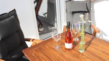 A wooden table with a bottle of red wine, two wine glasses, and a vase with flowers.