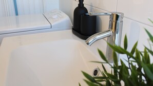 Ein Badezimmer mit einem weißen Waschbecken, einem schwarzen Seifenspender und einem weißen Handtuchwärmer.
