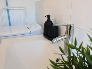 A bathroom with a white sink, a black soap dispenser, and a white towel warmer. - Flat 1, 55 sqm, 1 bedroom with double bed and 1 sofa bed, max. 4 persons (Burladingen)