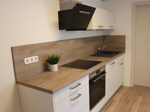 Una cocina moderna con encimera de madera, horno integrado y pileta.