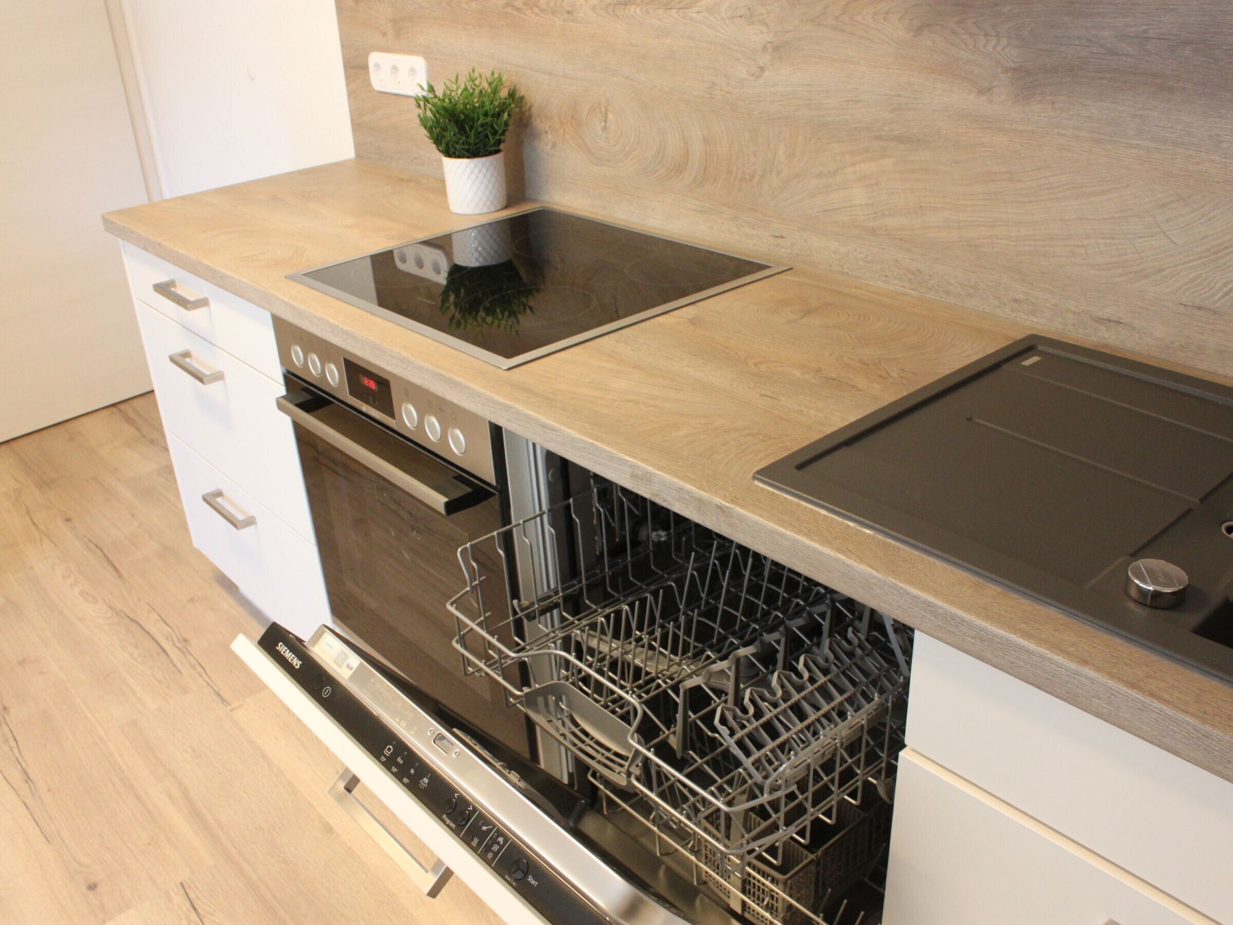 Eine Küche mit Geschirrspüler, Backofen und einer Holzausziehtafel.