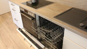 Eine Küche mit Geschirrspüler, Backofen und einer Holzausziehtafel.
