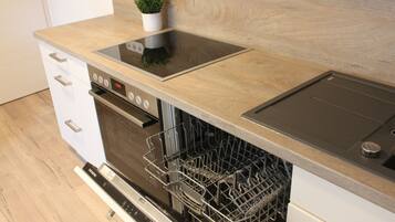 Eine Küche mit Geschirrspüler, Backofen und einer Holzausziehtafel.
