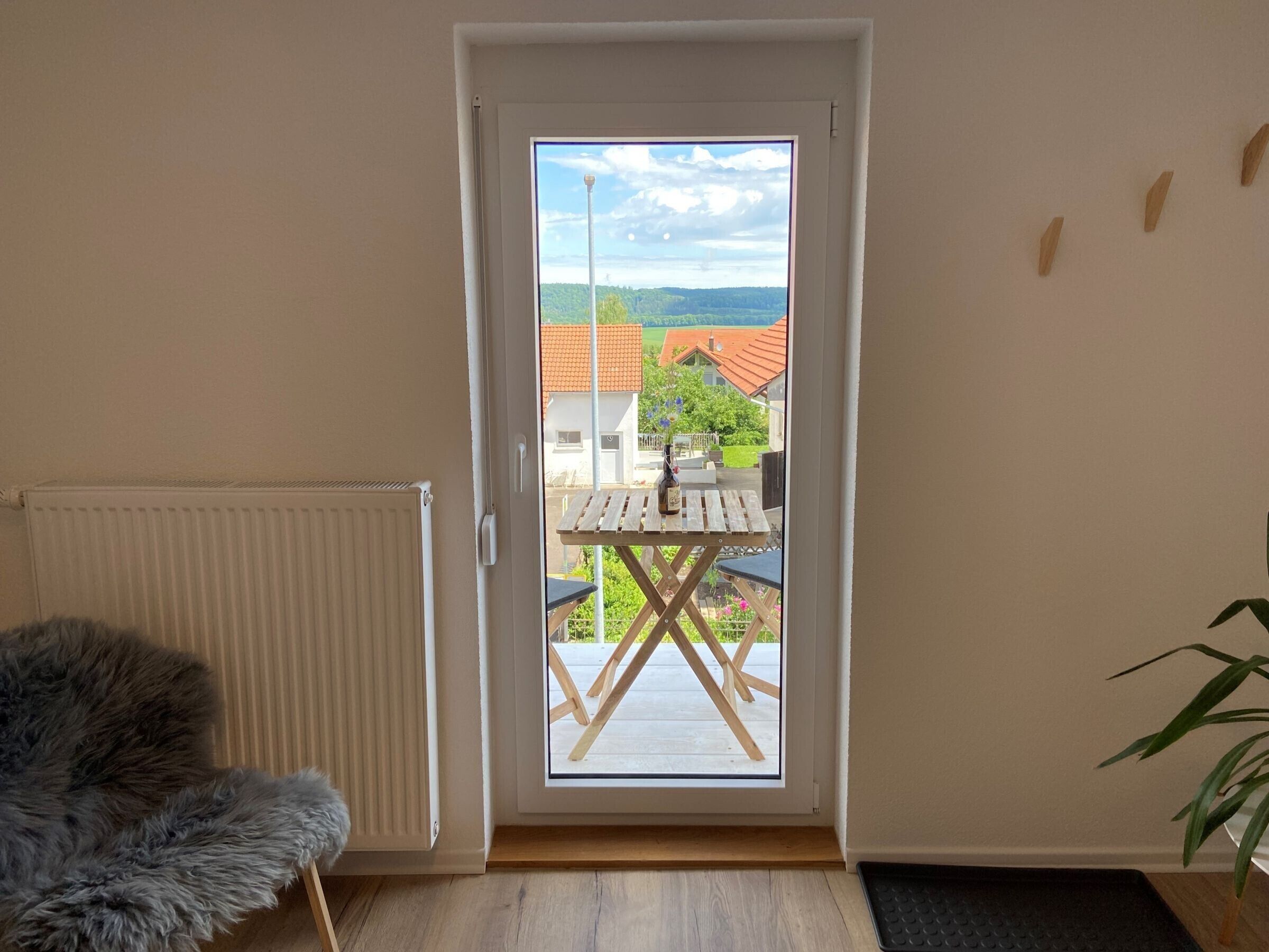 Quarto com porta para área externa, radiador, poltrona de pele e mesa com uma garrafa.