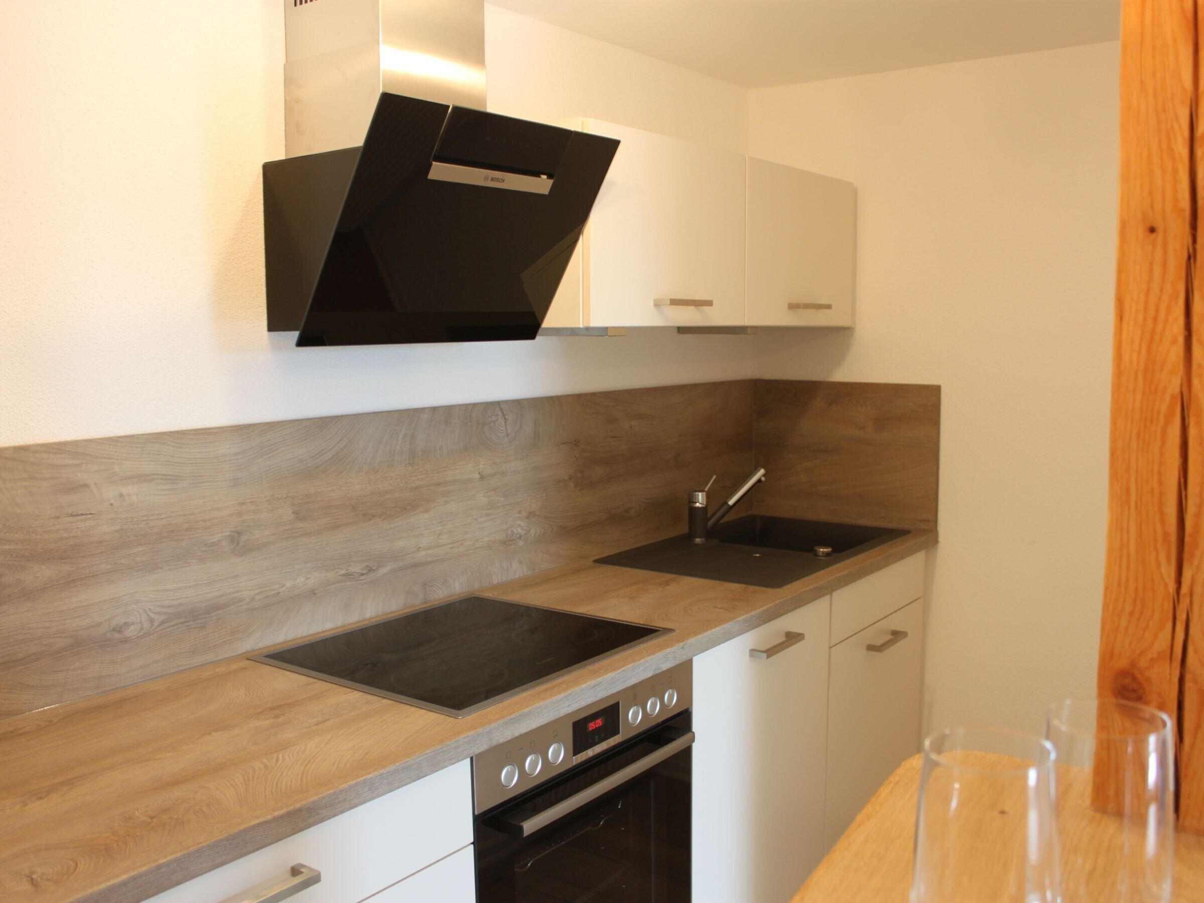 A modern kitchen with a built-in oven, a sink, and wooden countertops.