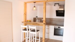 Une cuisine avec une table et des chaises en bois, un poêle et un luminaire suspendu.