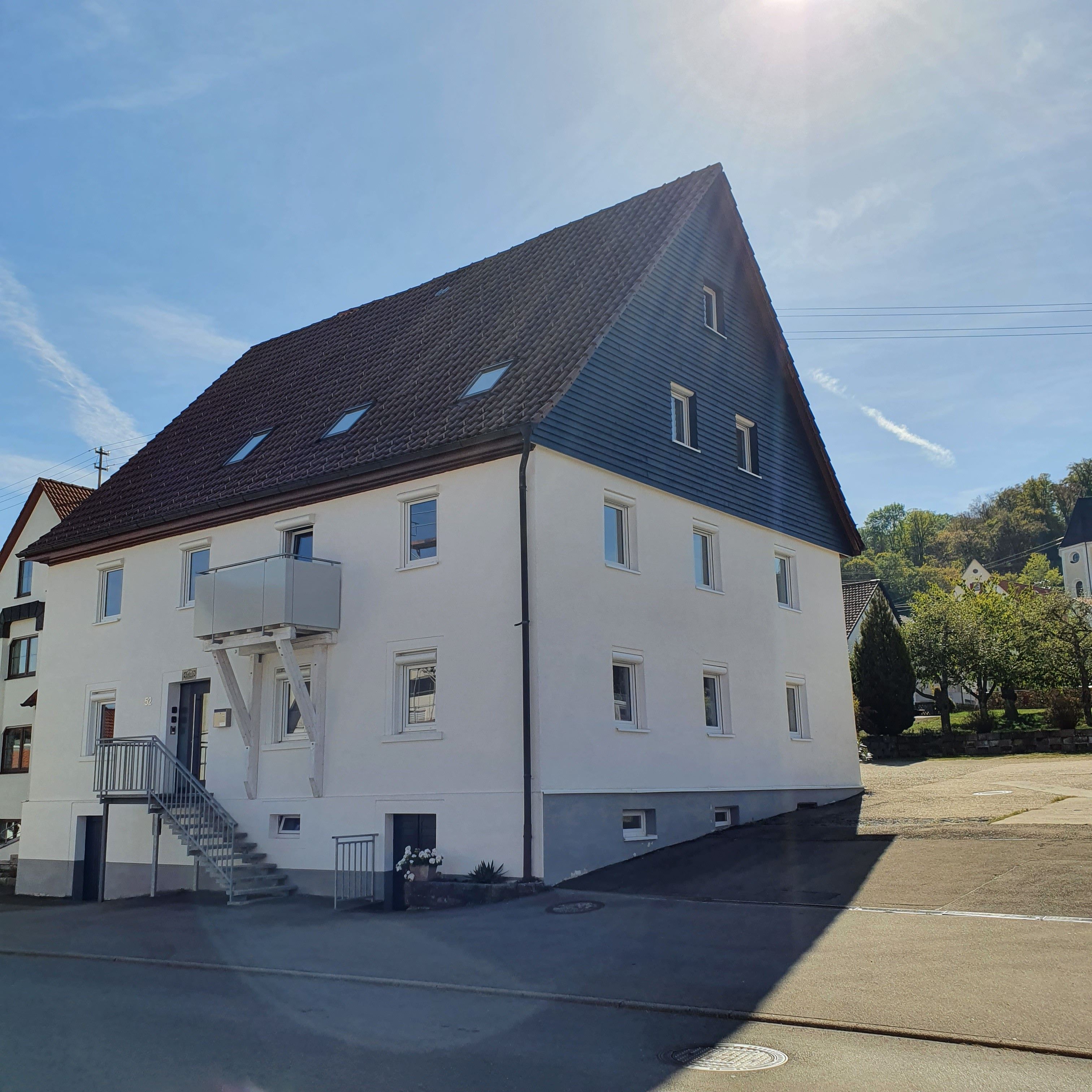 A two-story building with a sloped roof, multiple windows, and a small outdoor staircase leading to the entrance.