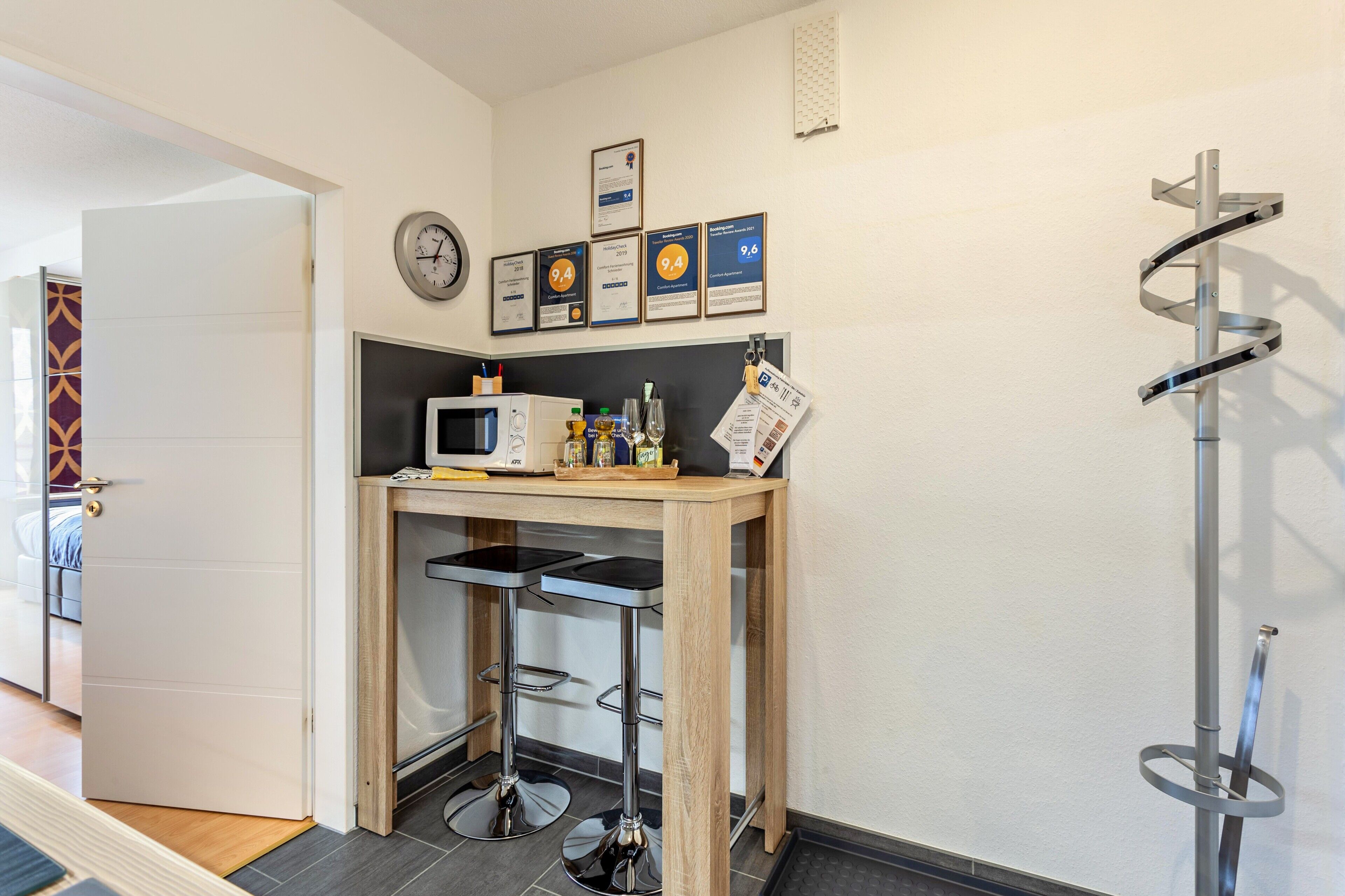 A kitchenette with a microwave, bar stools, and framed certificates on the wall.