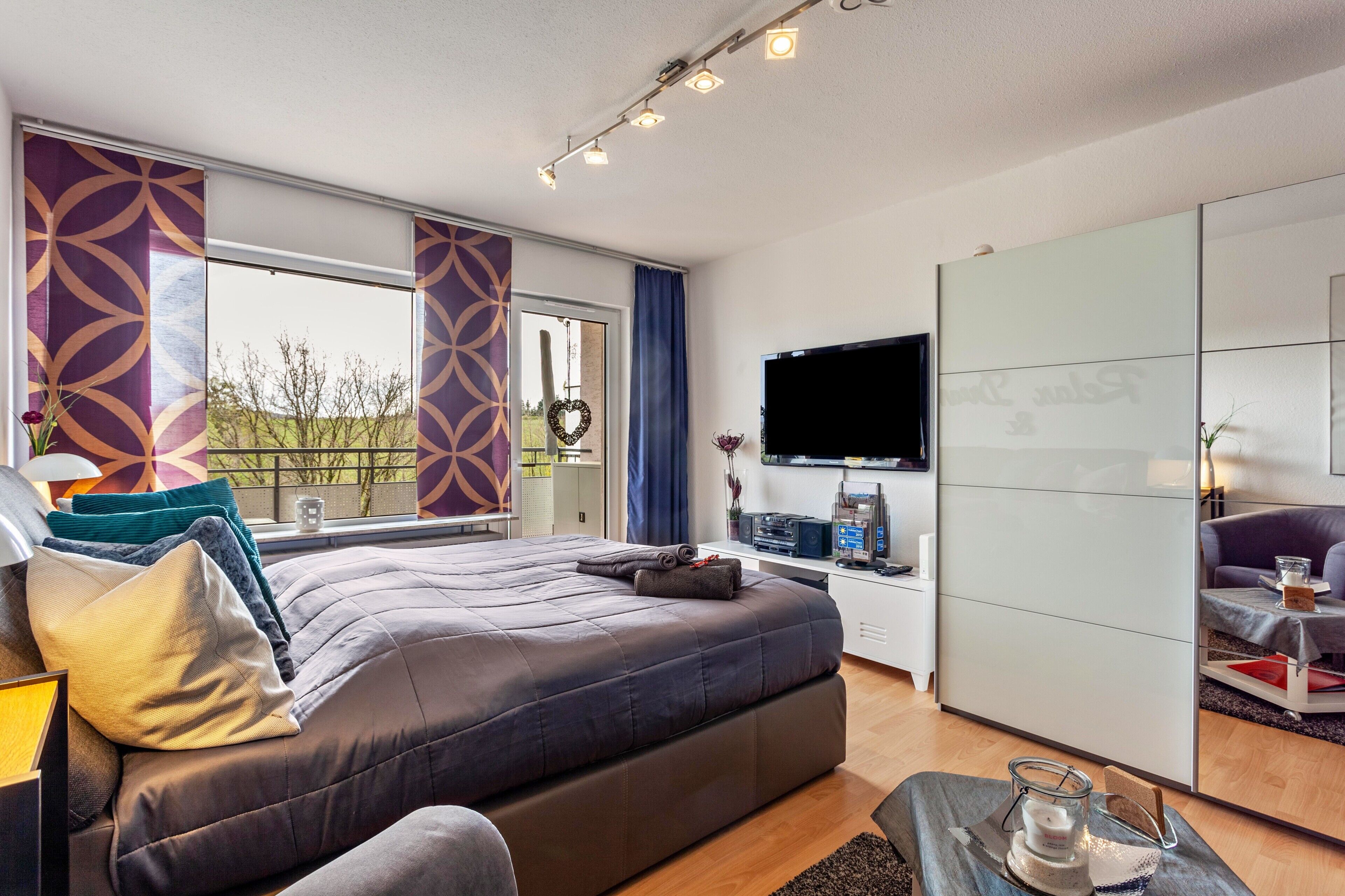 Quarto de hotel moderno com uma cama grande, televisão de tela plana e vista para o exterior.