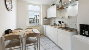 Una cocina moderna con armarios blancos, encimera negra y ventana con vista a una zona residencial.