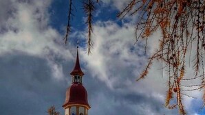A church with a red tower, surrounded by autumn trees and a grassy hill. - Apartment 'Priestereck' with Mountain View, Shared Terrace and Wi-Fi (Obernberg)