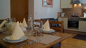 A dining table set with plates, glasses, and napkins, a candle, and a bottle.