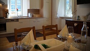 A kitchen with white cabinets, a dining table with chairs, and a window with curtains.
