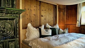 A wooden bed with white bedding, pillows, and a decorative pillow with a crest.