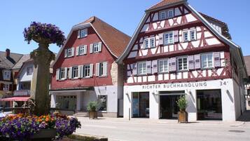 Ein traditionelles Fachwerkhäuschen mit einem Schild für 'RICHTER BUCHHANDLUNG' und einem Blumenbeet im Vordergrund.