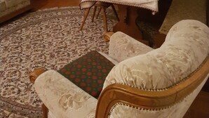 Un salon comprenant un canapé, une table à manger, un téléviseur et un tapis à motifs.