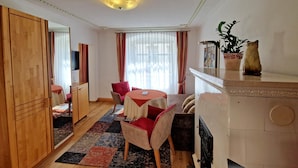Een kamer met een houten garderobe, een eettafel met stoelen, een bank, een televisie en een potplant.