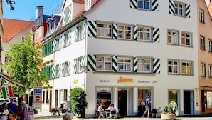 Een meerlaags gebouw met een café genaamd 'Bäckerei' en 'Konditorei - Café' op de begane grond.