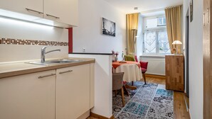 A compact kitchen with a sink, cabinets, and a dining area with a table and chairs.