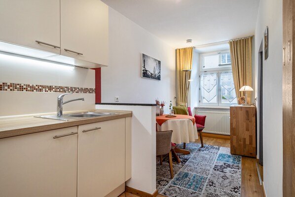 A compact kitchen with a sink, cabinets, and a dining area with a table and chairs.