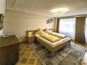A hotel room with a bed, bedside tables, a desk, a rug, and a wall decoration.