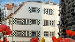 A building with a white facade and green window frames, surrounded by a field of poppies. - Apartment 'Ferienwohnung S5' with Wi-Fi (Lindau am Bodensee)