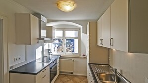 A compact kitchen with a built-in oven, a sink, and a window with blinds. - Apartment 'Ferienwohnung S5' with Wi-Fi (Lindau am Bodensee)
