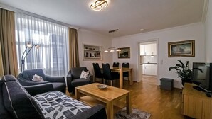 A modern living room with a sofa, chairs, a dining table, and a TV. - Apartment 'Ferienwohnung S5' with Wi-Fi (Lindau am Bodensee)