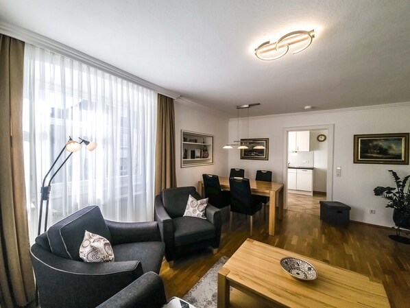 A modern living room with a sofa, chairs, a coffee table, and a dining area.
