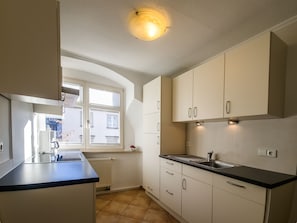 A kitchen with white cabinets, a black countertop, a window, and a ceiling light.