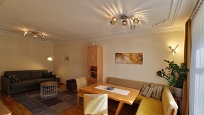 A modern living room with a sofa, a dining table, and a wooden cabinet. - Apartment 'Ferienwohnung S6' with Wi-Fi (Lindau am Bodensee)