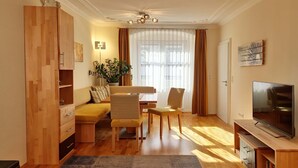 A modern living room with a sofa, chairs, a dining table, a TV, and a wooden cabinet. - Apartment 'Ferienwohnung S6' with Wi-Fi (Lindau am Bodensee)