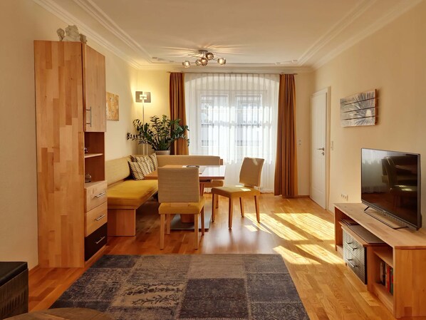 En moderne stue med sofa, stole, spisebord, fjernsyn og et træskab.