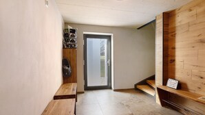 A hallway with a wooden bench, a door with a glass panel, and a wooden wall with a shelf. - Panorama Suite Apartment with Balcony, Grill Hut and Infrared Cabin (Donaueschingen)