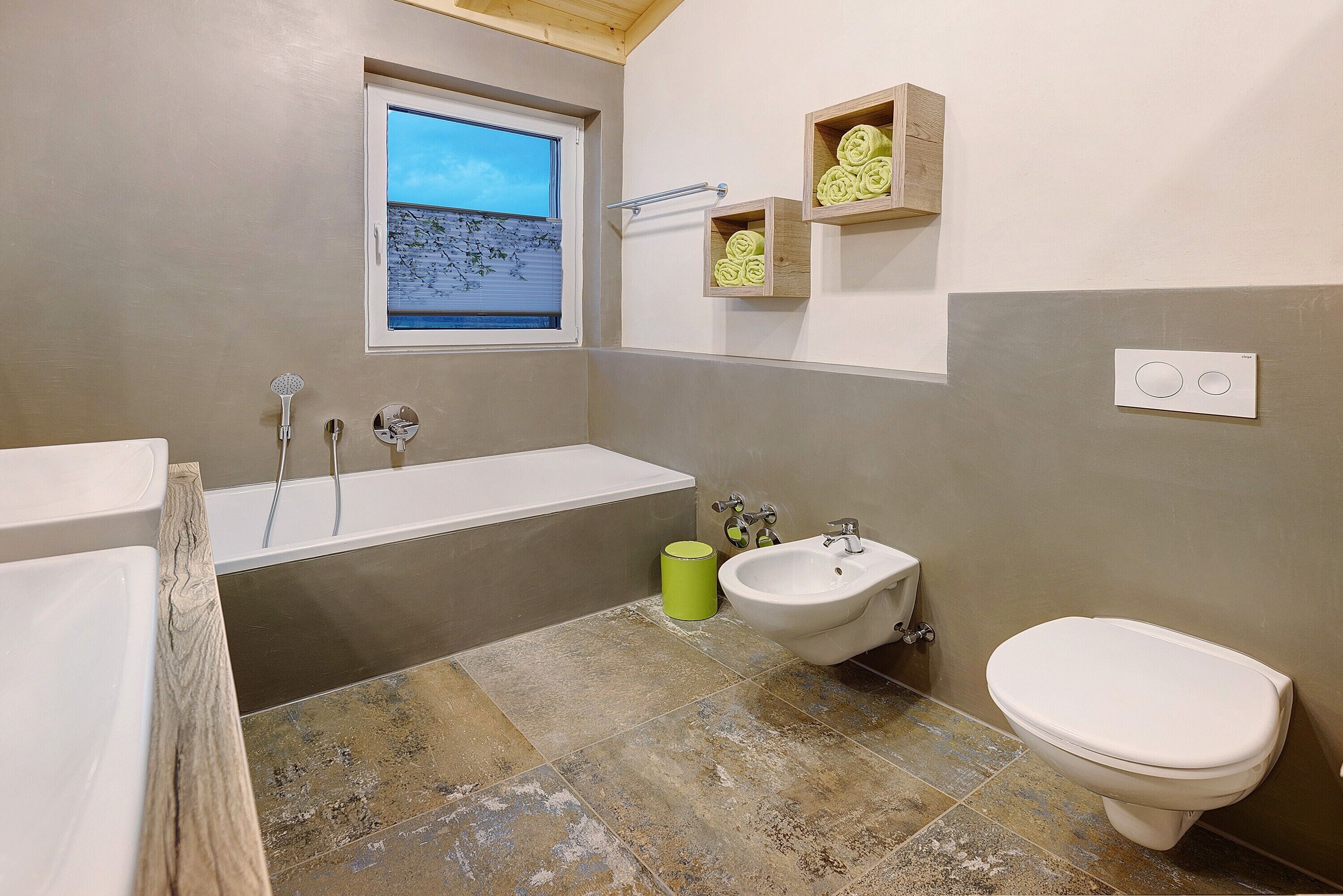 Ein Badezimmer mit Badewanne, Bidet, Toilette und einem Fenster mit Blick.