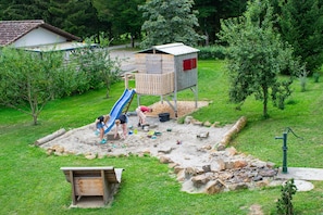 A playground with a slide, sandpit, and wooden play structures.