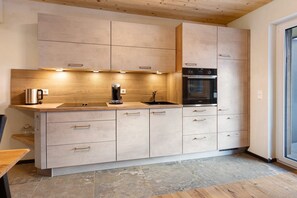 A modern kitchen with light wood cabinetry, a stainless steel sink, and a built-in oven. - Kuschel Apartment with Balcony, Barbecue Hut, and Infrared Cabin (Donaueschingen)