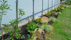 A landscaped garden with various plants and a metal fence. - Apartment 'Ebbi' with Balcony, Accessible, Dogs Allowed, BBQ Hut & Infrared Cabin (Donaueschingen)
