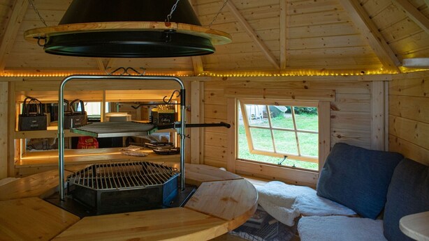 A cozy cabin interior with a grill, a window with a view, and a seating area.