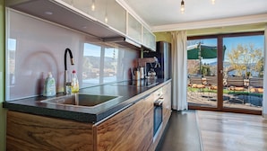 A modern kitchen with a large island, built-in cabinets, and a sliding glass door leading to an outdoor patio. - Apartment 'Freiraum' with Mountain View, Private Terrace and Wi-Fi (Weiler Simmerberg)