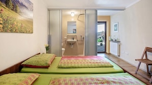 A bedroom with two beds, a bathroom with a sink, and a view of the outdoors. - Apartment 'Freiraum' with Mountain View, Private Terrace and Wi-Fi (Weiler Simmerberg)