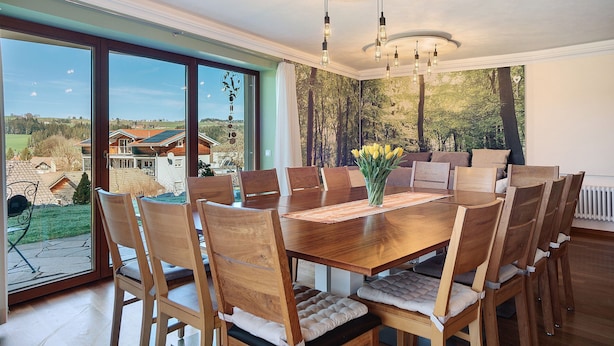 A dining area with a large wooden table, multiple chairs, and a view of the outdoors. - Apartment 'Freiraum' with Mountain View, Private Terrace and Wi-Fi (Weiler Simmerberg)