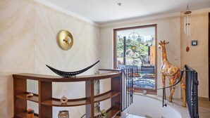 Un intérieur moderne avec une console en bois aux lignes courbes, une sculpture de girafe et une vue sur l’extérieur.