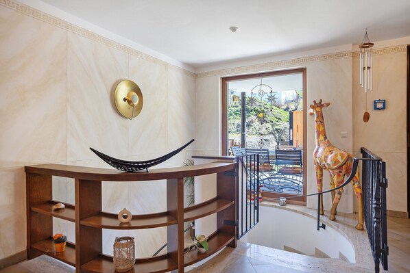 A modern interior with a curved wooden console table, a giraffe sculpture, and a view of the outdoors.