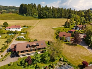 An aerial view of a rural area with houses, fields, and a large building with a red roof. - Apartment 'Lichtblick' with Mountain View, Balcony and Wi-Fi (Weiler Simmerberg)