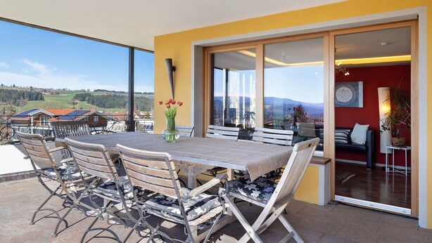 Un coin repas avec une table et des chaises, un vase de fleurs et une vue sur le paysage.