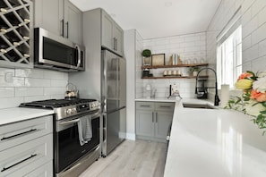 A modern kitchen with stainless steel appliances, a wine rack, and a built-in oven. - Petite Perfection | Grason Properties (Puyallup)